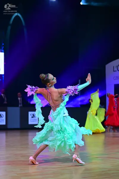 Dancesport competitor: Female dancer in foreground: mint green multi-layered ruffled latin dance dress 