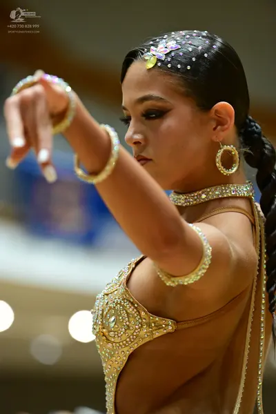 Dancesport competitor: Female dancer: gold Latin dance costume heavily embellished with rhinestones and