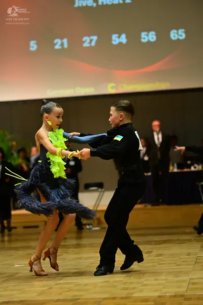 Dancesport competitor: Male dancer: black long-sleeved shirt and black trousers with a small yellow and