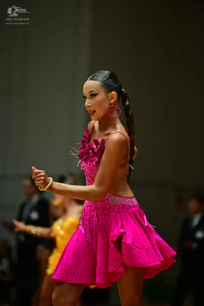 Dancesport competitor: Female dancer: bright pink Latin dress with thin straps and subtle embellishment