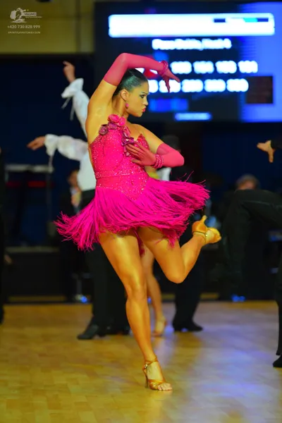 Dancesport competitor: Female dancer: bright pink latin dress with a sequined bodice, floral embellishm