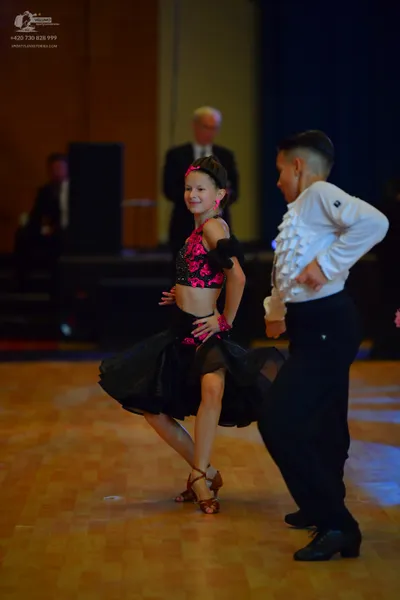 Dancesport competitor: Female dancer: pink and black latin dance dress with a black skirt and a pink pa