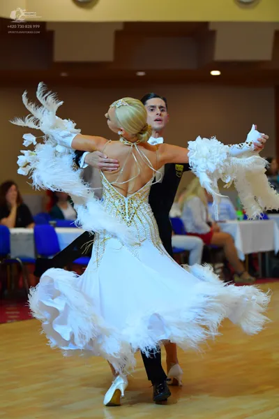 Dancesport competitor: Female dancer: white ballroom dress featuring gold sequin detailing on the bodic