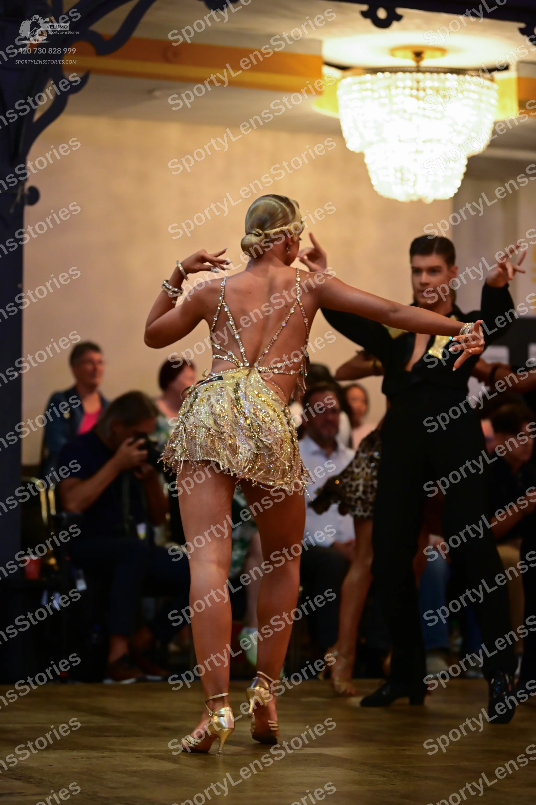 Dancesport competitor: Female dancer: gold sequined short Latin dress with thin straps and an open back