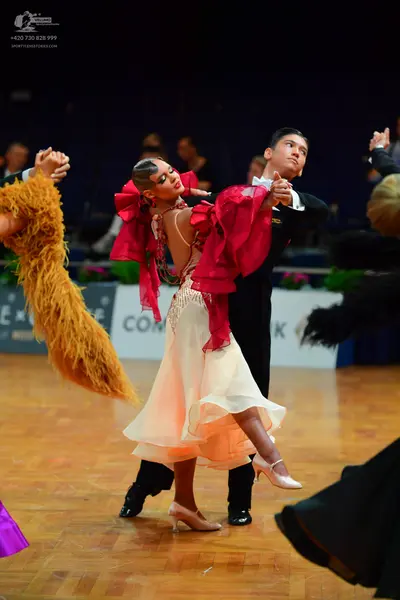 Dancesport competitor: Female dancer: red and cream Latin dance dress with a large, flowing red ruffled