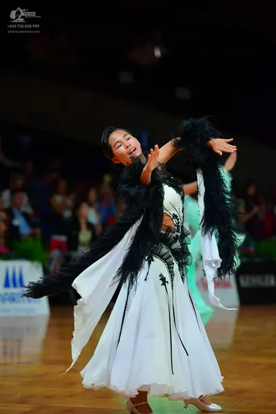 Dancesport competitor: Female dancer: white ballgown with black feather or lace embellishments