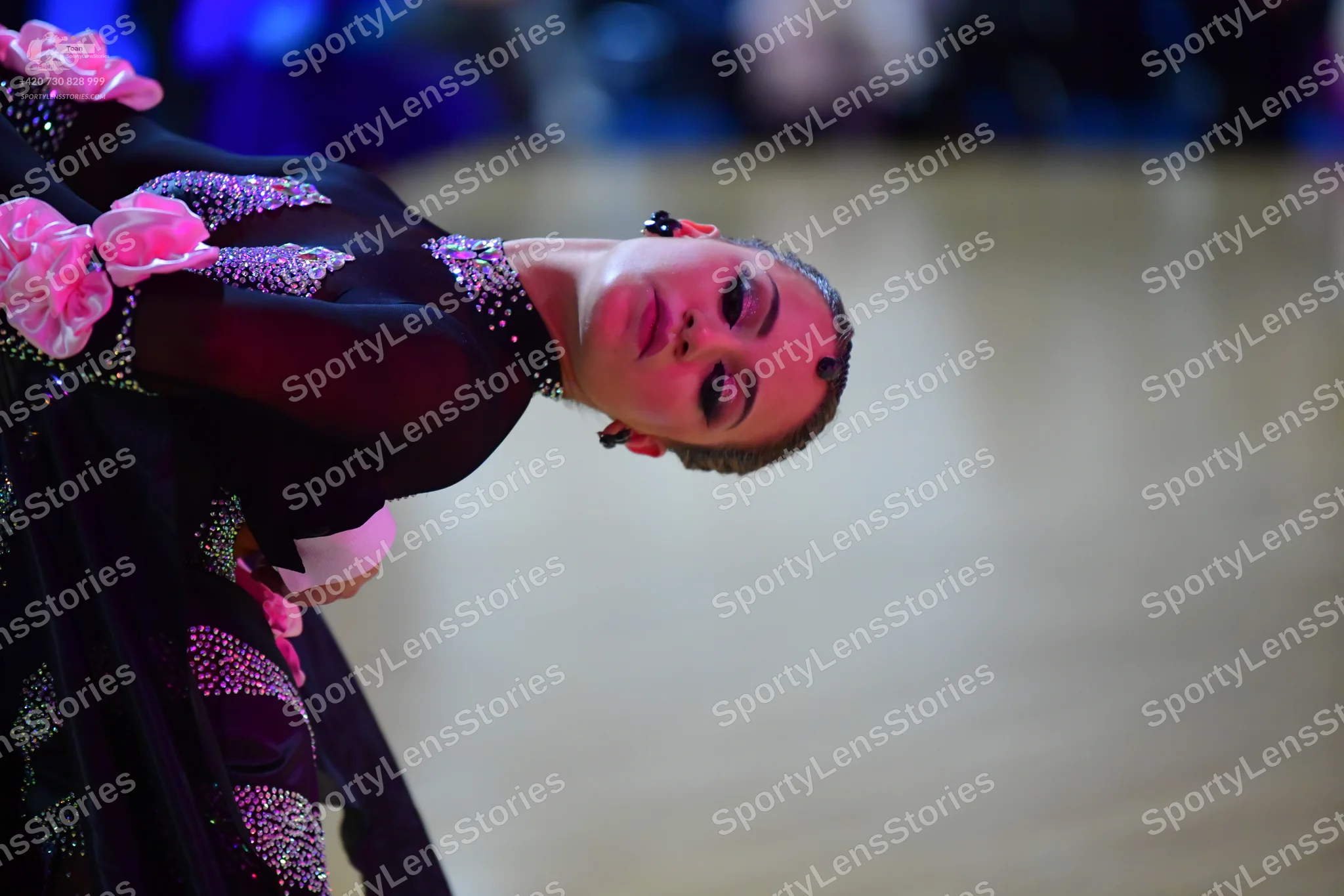 Dancesport competitor: Female dancer: black dress with large pink fabric flowers and extensive pink and