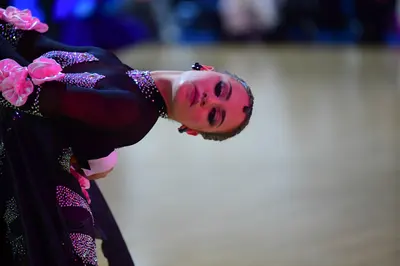 Dancesport competitor: Female dancer: black dress with large pink fabric flowers and extensive pink and