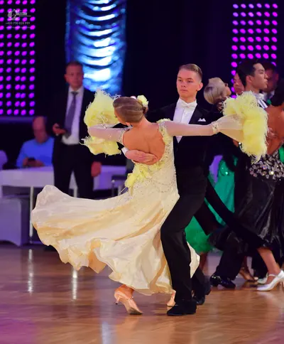 Dancesport competitor: Female dancer: cream-colored ballgown with a full, flowing skirt and large, fluf