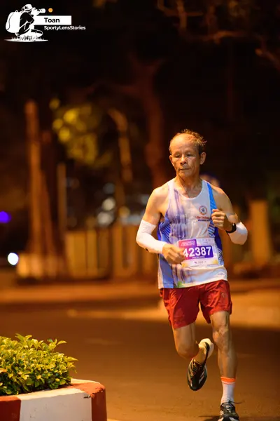 Marathon runner #42387: Runner 1: light blue and white tank top, red shorts, white arm sleeves, dark run