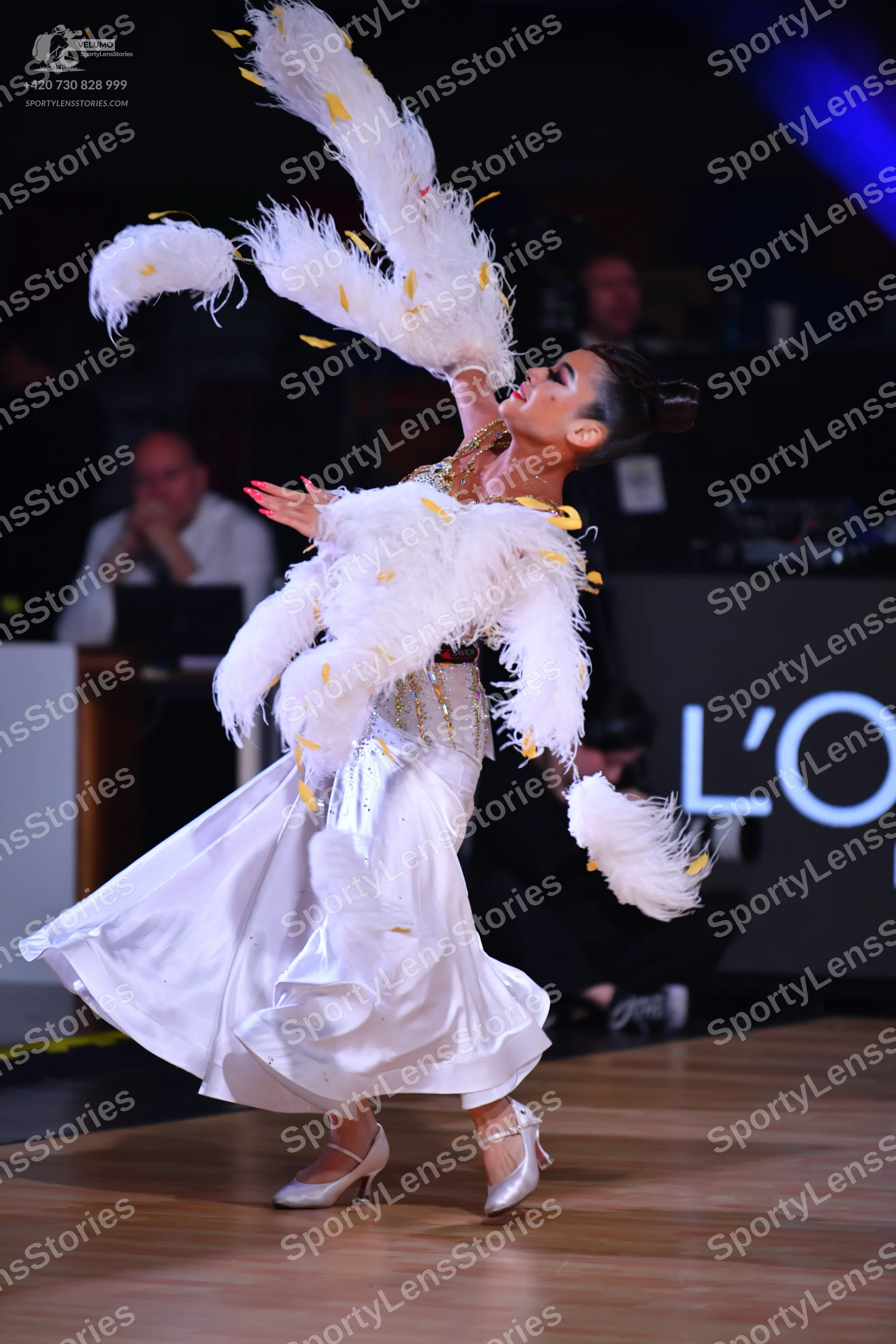 Dancesport competitor: Female dancer: white ballgown with a voluminous skirt and large white feather ac