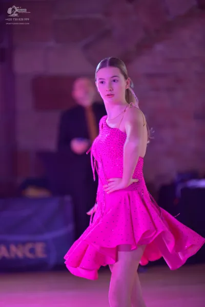 Dancesport competitor: Female dancer: bright pink latin dress with sequins and a ruffled skirt