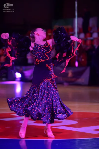 Dancesport competitor: Female dancer: black latin dress with pink polka dots, featuring large black ruf