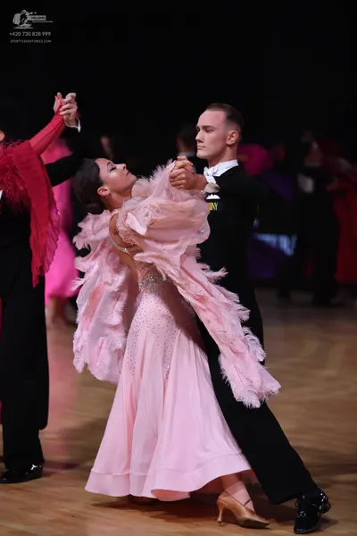 Dancesport competitor: Female dancer: light pink ballgown with voluminous, feathery pink trim and sequi