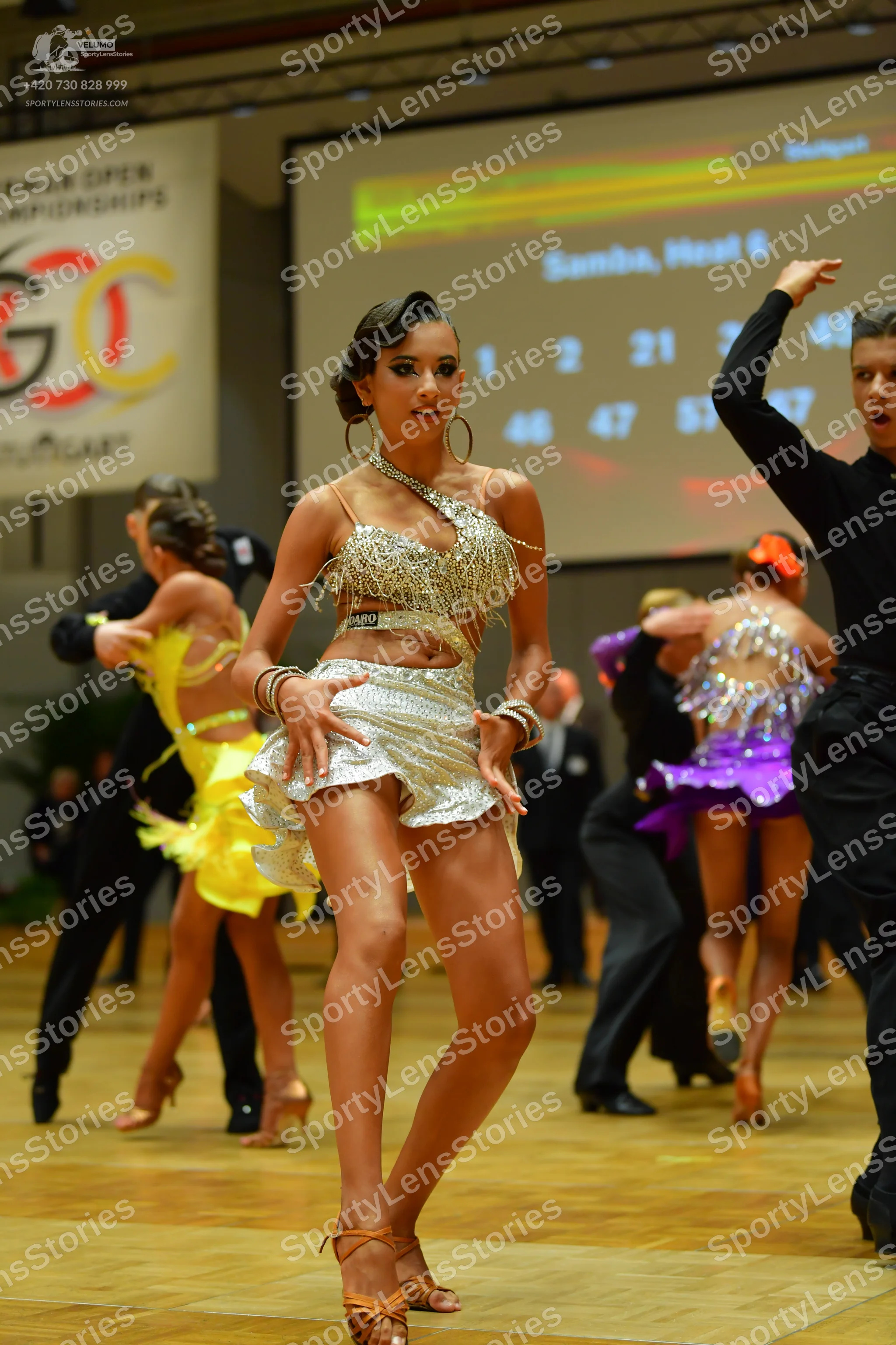 Dancesport competitor: Main female dancer: silver sequined Latin dress with thin straps and cutouts, la