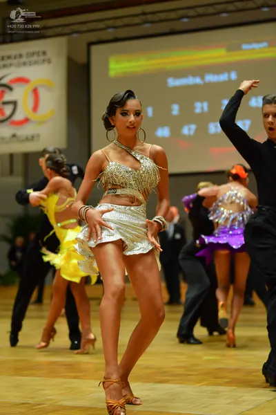 Dancesport competitor: Main female dancer: silver sequined Latin dress with thin straps and cutouts, la