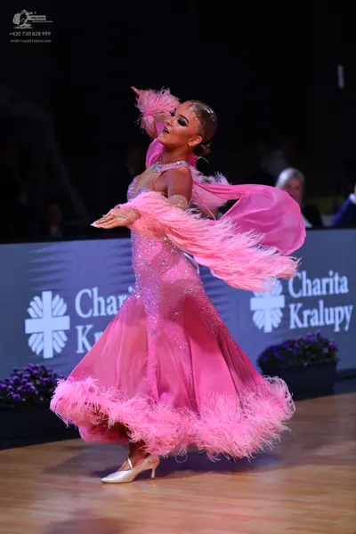 Dancesport competitor: Female dancer: bright pink ballgown with a sequined bodice, a voluminous sheer p