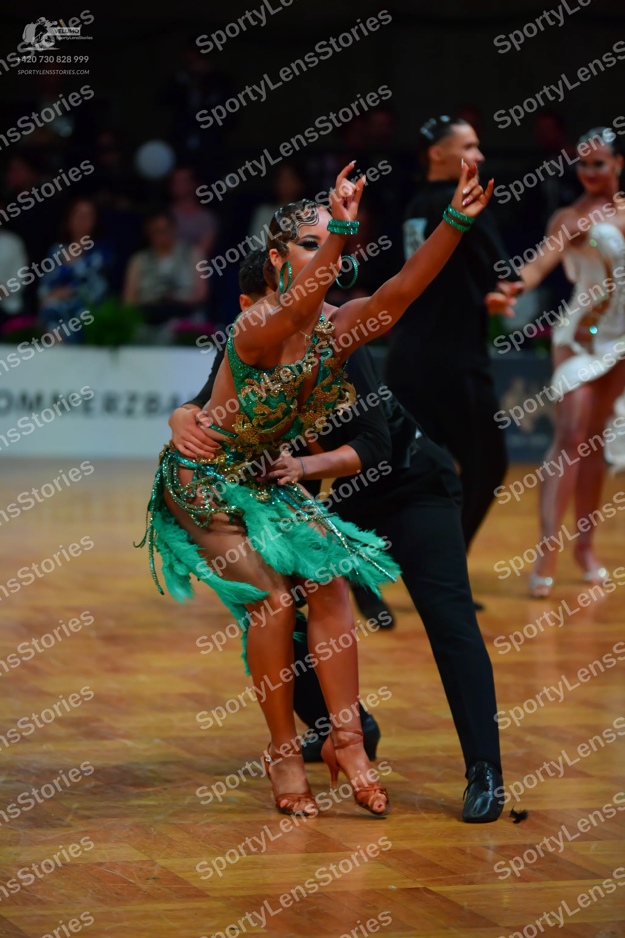 Dancesport competitor: Main female dancer: green Latin dress with gold/bronze sequins and teal fringe o