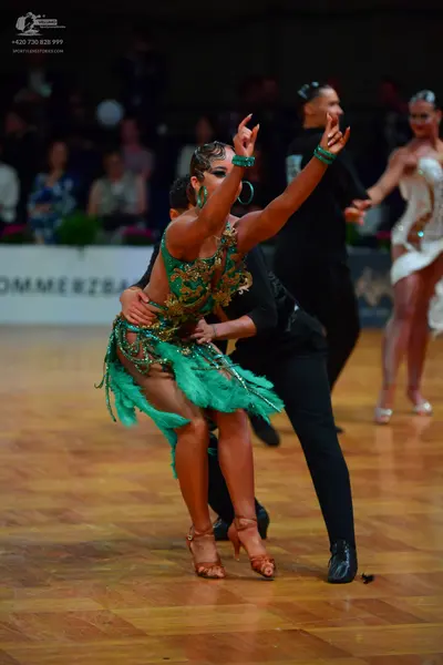 Dancesport competitor: Main female dancer: green Latin dress with gold/bronze sequins and teal fringe o