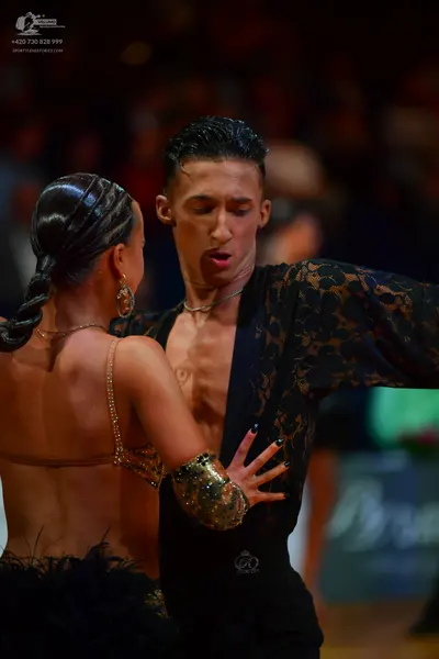 Dancesport competitor: Male dancer: black shirt with lace-patterned sleeves, worn open at the chest, an