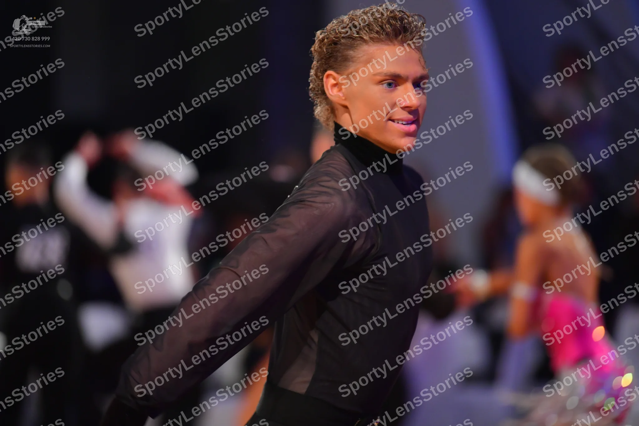 Dancesport competitor: Male dancer (foreground): black long-sleeved shirt with sheer sleeves