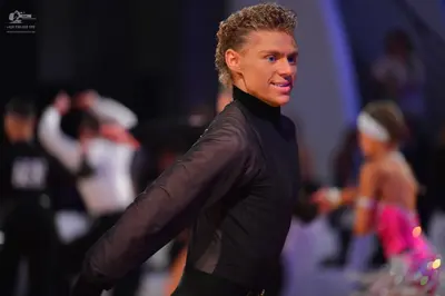 Dancesport competitor: Male dancer (foreground): black long-sleeved shirt with sheer sleeves