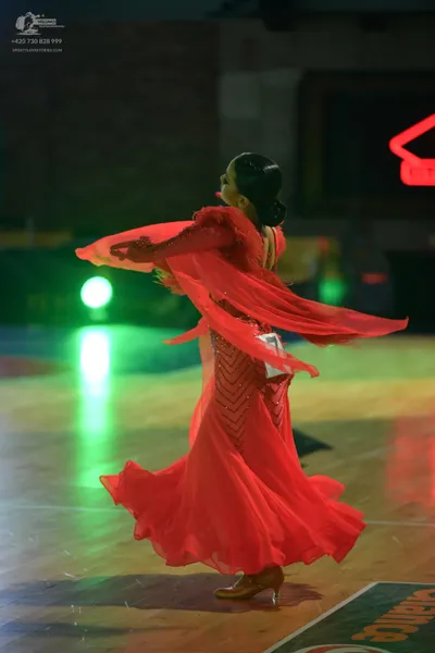 Dancesport competitor: Female dancer: red ballroom dress with a voluminous, flowing skirt and long slee