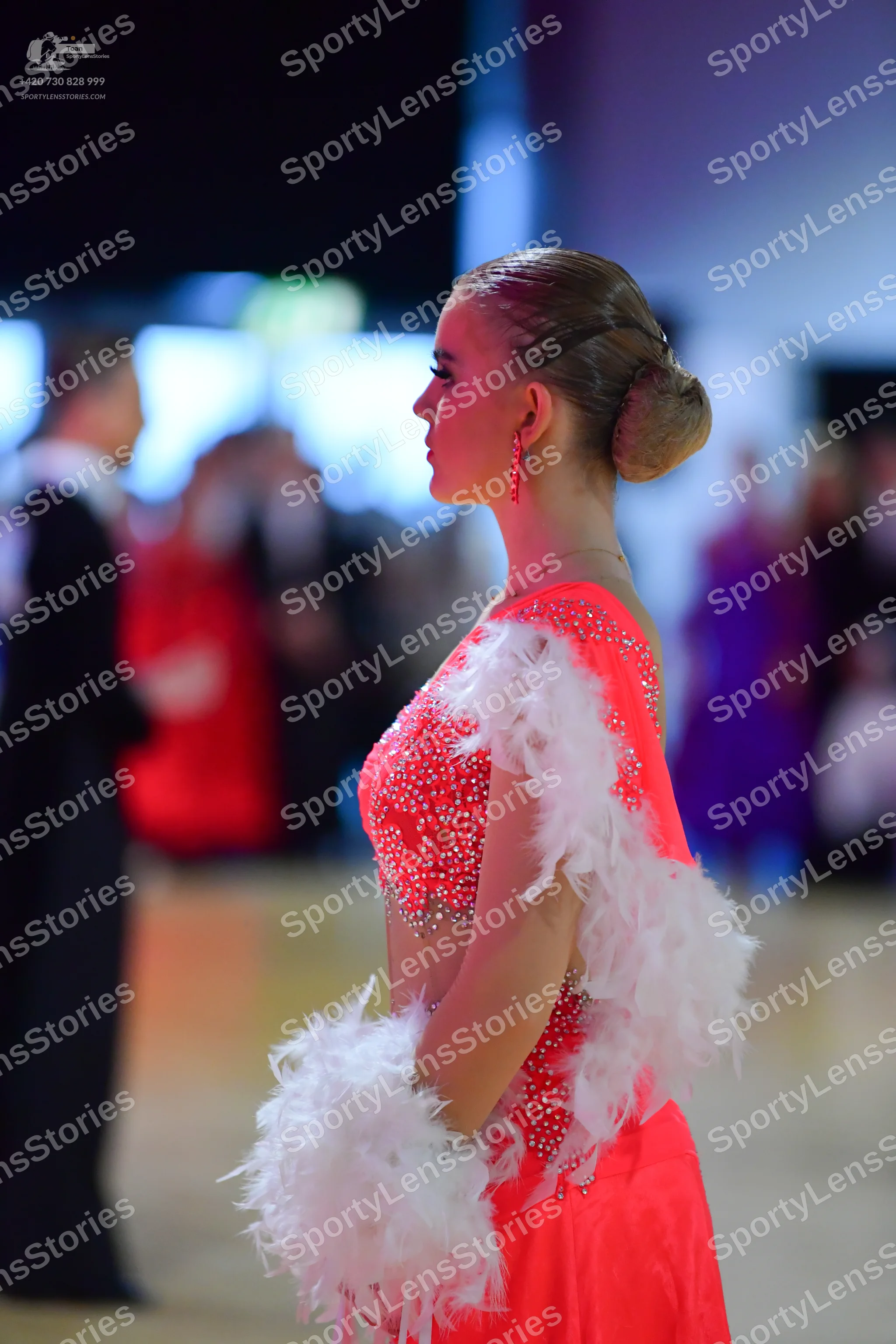 Dancesport competitor: Female dancer: coral Latin dance costume with rhinestone embellishments on the b