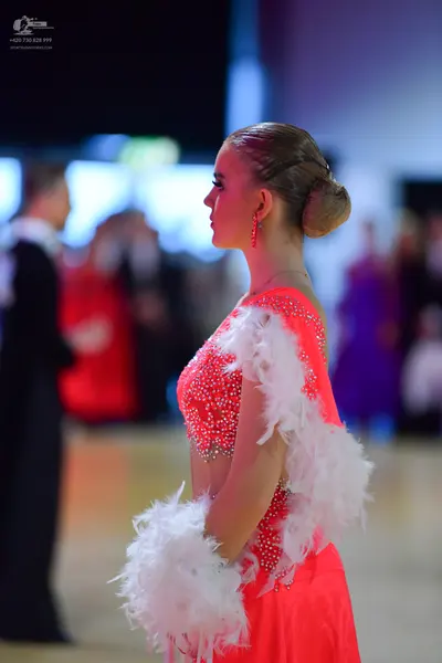 Dancesport competitor: Female dancer: coral Latin dance costume with rhinestone embellishments on the b