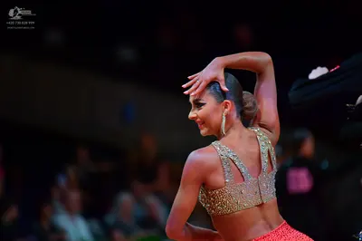 Dancesport competitor: Female dancer: gold/silver sequined crop top and red sequined skirt with large d