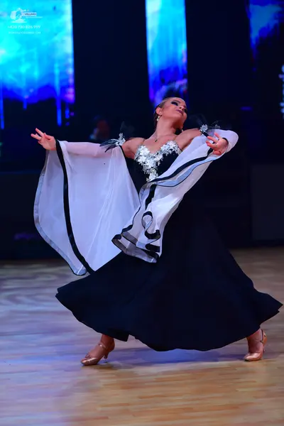 Dancesport competitor: Female dancer: black ballgown with a white and black accented bodice and large, 