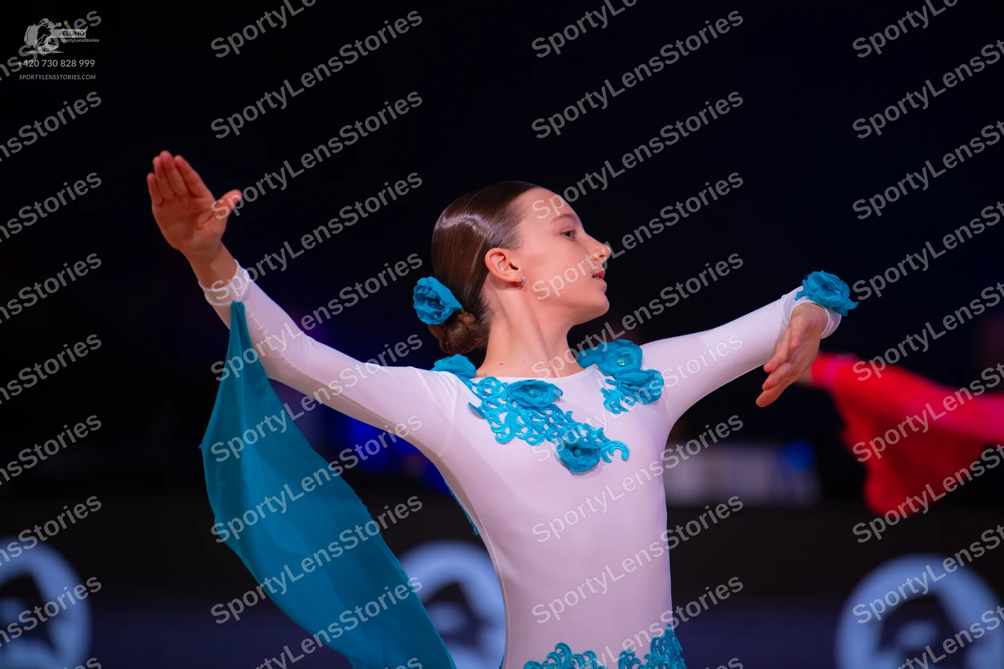 Dancesport competitor: Female dancer: white long-sleeved latin dress with teal floral appliques and a l