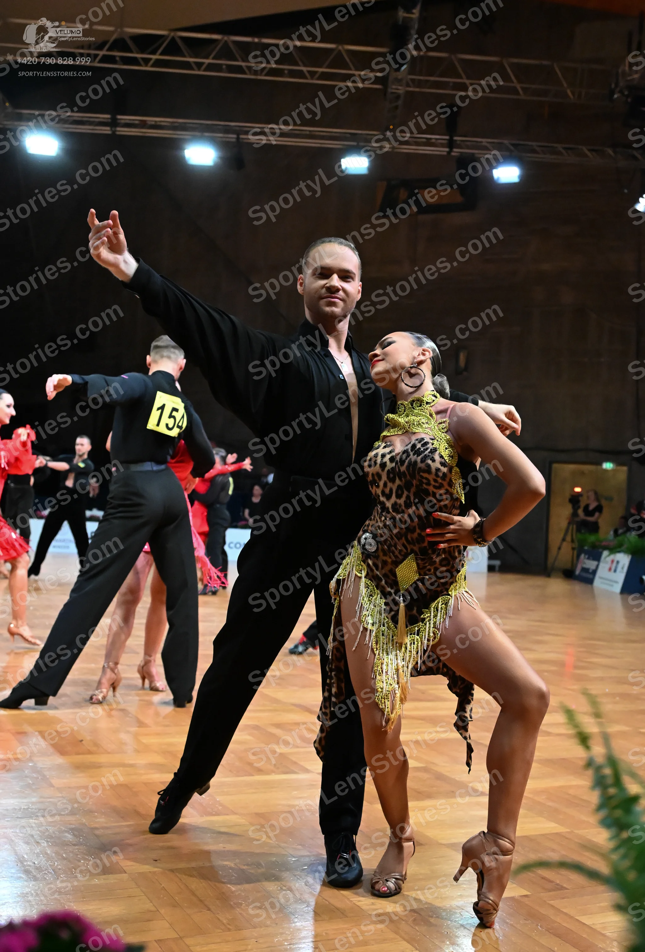 Dancesport competitor #154: Male dancer in foreground: black long-sleeve shirt and black trousers