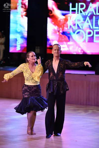 Dancesport competitor: Female dancer: yellow lace long-sleeved top with a V-neck and a black skirt with