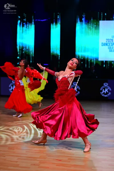 Dancesport competitor: Female dancer in background: red ballroom dress with a large skirt