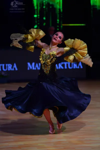 Dancesport competitor: Female dancer: dark blue ballroom gown with a gold and black sequined bodice and