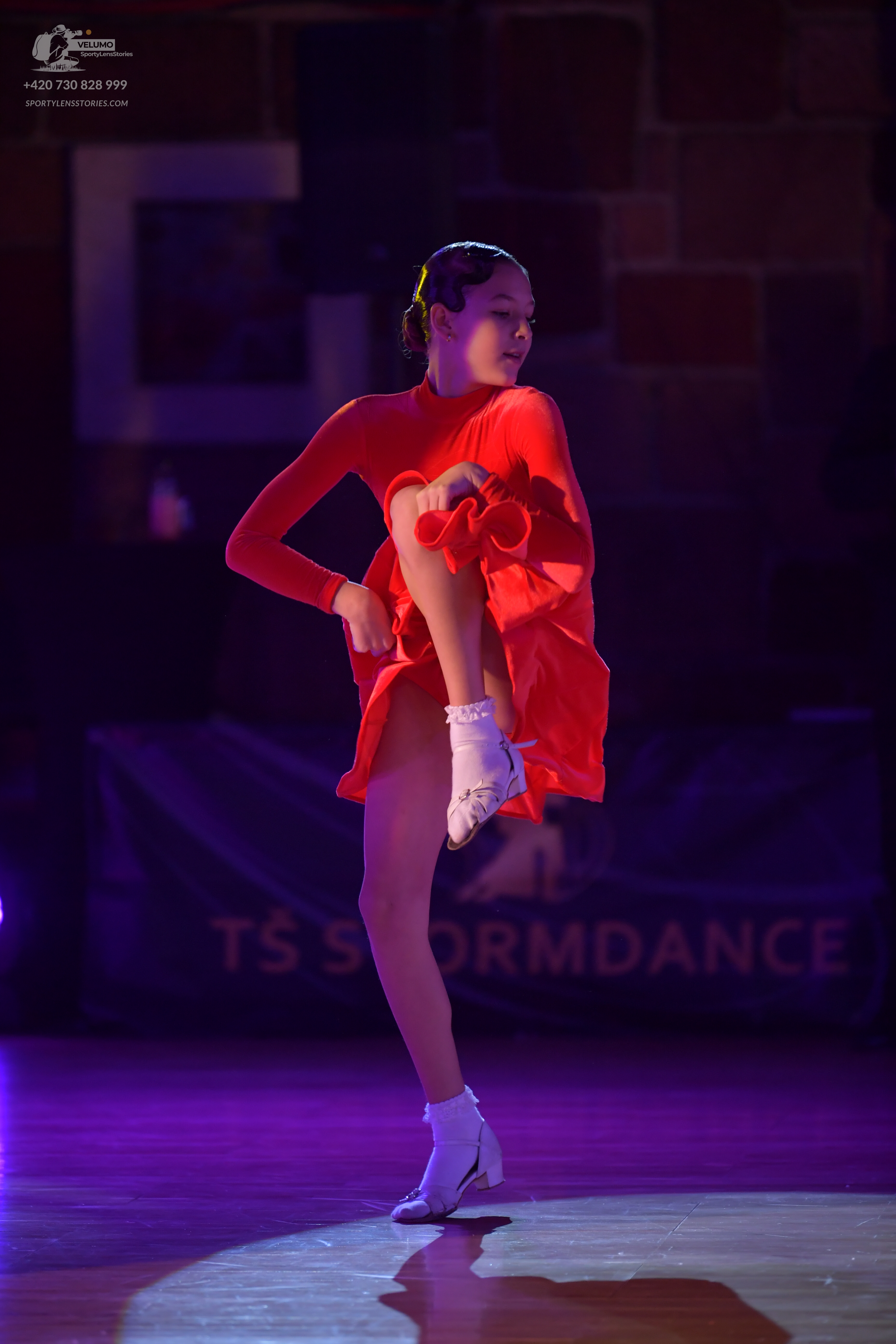 Dancesport competitor: Female dancer: red long-sleeved Latin dress and white dance shoes