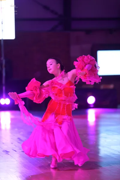 Dancesport competitor: Female dancer: bright pink latin dress with large ruffles on the sleeves and a f