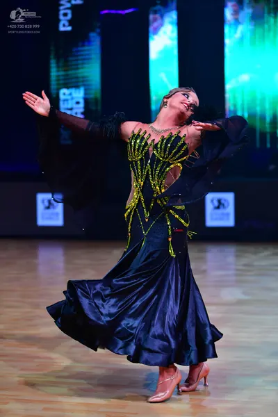 Dancesport competitor: Female dancer: Dark navy or black ballroom dress with a full, flowing satin skir