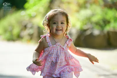 Dancesport competitor: The child is wearing a pink and white gingham patterned sleeveless dress with ru