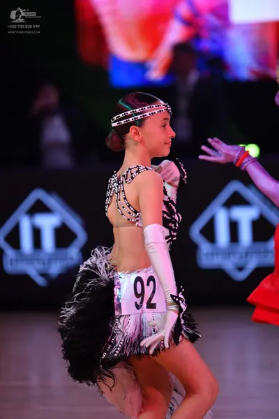 Dancesport competitor: Female dancer: white and black Latin dress with sequins and long fringe, white l