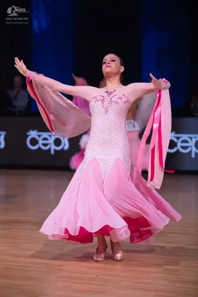Dancesport competitor: Female dancer: light pink ballroom gown with a heavily sequined bodice, floral e
