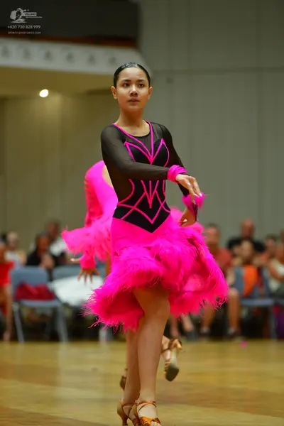 Dancesport competitor: Female dancer: black and bright pink latin dance dress with long sleeves and a v
