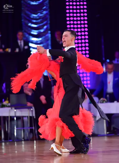 Dancesport competitor: Male dancer: black long-sleeved top, black trousers, and black sequined dance sh