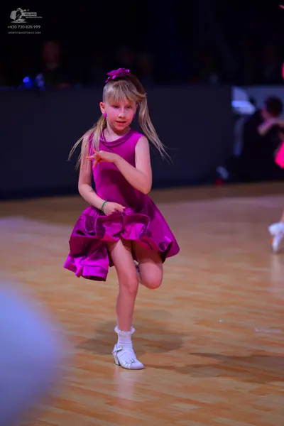 Dancesport competitor: Female dancer: magenta sleeveless dress with a flared, voluminous skirt, a match