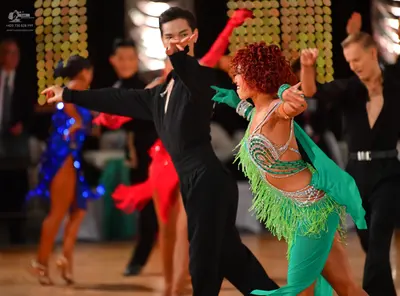 Dancesport competitor: Foreground male dancer: black long-sleeved dance shirt and black trousers