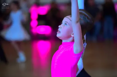 Dancesport competitor: Female dancer in foreground: bright pink sleeveless Latin-style top