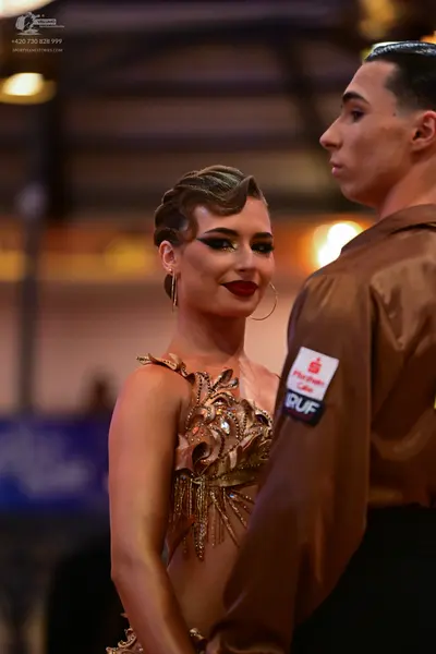 Dancesport competitor: Female dancer: bronze/gold Latin dress featuring metallic/sequin floral patterns