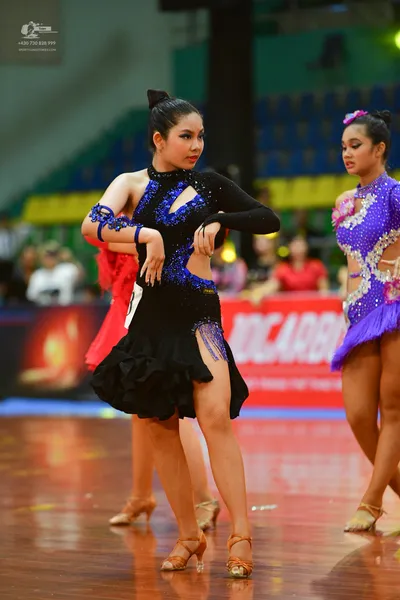 Dancesport competitor: Female:  Deep blue, fitted Latin dress with a halter neckline and a low-cut back