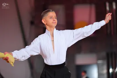 Dancesport competitor: Male dancer: white long-sleeved shirt with a pleated front and a deep V-neck, bl